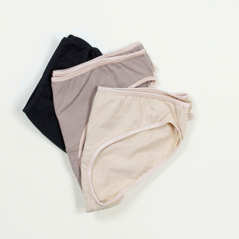 three pairs of underwear in beige, black, and neutrals on a plain background.